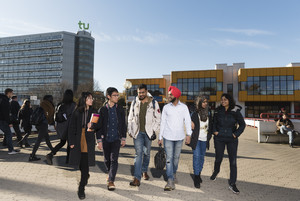 Eine Gruppe internationaler Studierender läuft über die Mensabrücke. Im Hintergrund der Mathetower und die Mensa.